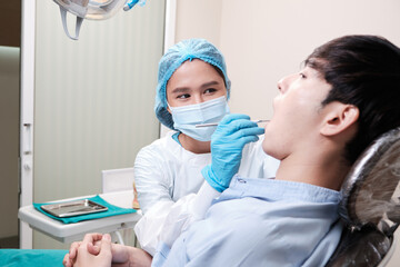 Asian female dentist examine young male patient teeth and toothache stomatology in dental clinic, well-being hygiene checks, and professional orthodontic healthcare work in doctor's office hospital.