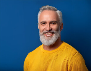 Obraz premium Portrait of Mature Handsome Man Happily Smiling Against Blue Studio Background