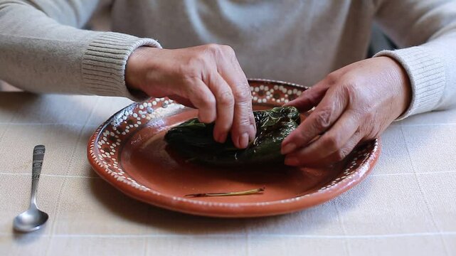 Woman removes the husk from a poblano chili