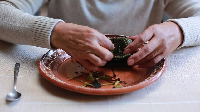 Woman removes the husk from a poblano chili