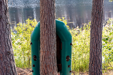 beautiful summer landscape with a lake, green rubber boat on the shore of the lake, wild aquatic plants