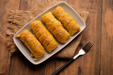 cheese roll cake on white plate on wooden table