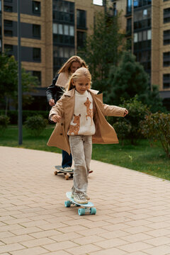 Mom and daughter skateboard in a city park