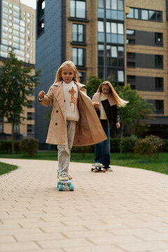 Mom teaches her daughter to skateboard in a city park