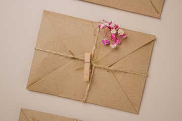 Envelope made of craft paper with dried flowers on a beige background. Letter in an envelope