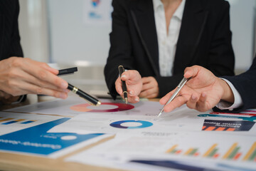 Strategic Business Meeting: Close-up shot of hands pointing at financial charts and graphs during a business meeting, emphasizing collaboration and analysis.