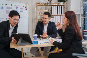 Business Meeting: Strategy Session: A diverse team of professionals, dressed in business attire, engage in a focused discussion, analyzing data and charts on a tablet and whiteboard.