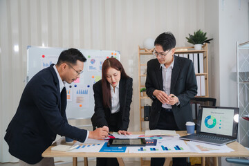 Business Professionals Collaborate: A diverse team of professionals gathers around a table filled with financial reports, analyzing data and collaborating on a project.
