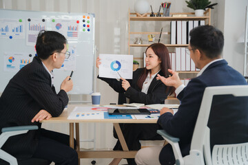 Strategic Business Meeting:  A professional woman presents a pie chart to her colleagues during a focused business meeting, illustrating a collaborative and data-driven approach to success. 