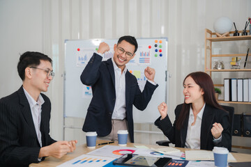 Business Success Celebration: A diverse team of young professionals, dressed in business attire, celebrates a successful presentation or meeting, showcasing their unity and triumph.