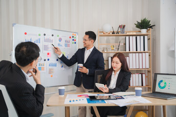 Strategic Business Meeting: A diverse team collaborates on a project, analyzing data on a whiteboard in a modern office setting. The image conveys professionalism, teamwork, and insightful discussion.