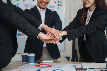 United We Stand: A diverse team of business professionals show their unity and collaboration by placing their hands together in a powerful symbol of teamwork.