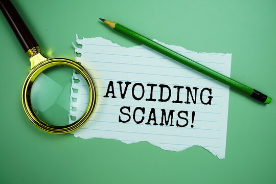 Avoiding Scam! quotes text on paper torn with magnifying glass top view on green background