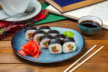 Japanese rolls with red fish on a plate, cafe, restaurant, on a wooden table.