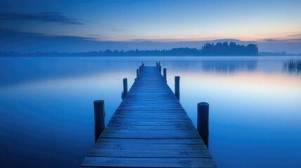 Obraz premium Blue hour over a calm lake, with a wooden pier stretching out into the water