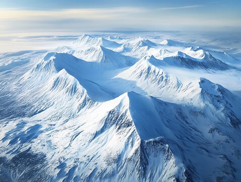 Aerial view of snow-covered mountain range under a clear sky.