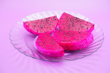 dragon fruit slices on a clear glass plate. dragon fruit slices isolated on a purple background