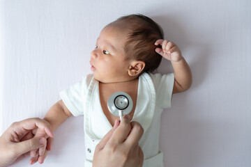 A newborn baby lying down during a health checkup, calmly resting as the doctor carefully checks her well-being and overall health.