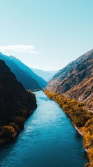 Obraz premium Serene River Flowing Through Majestic Mountains Under a Clear Blue Sky in Nature's Beauty