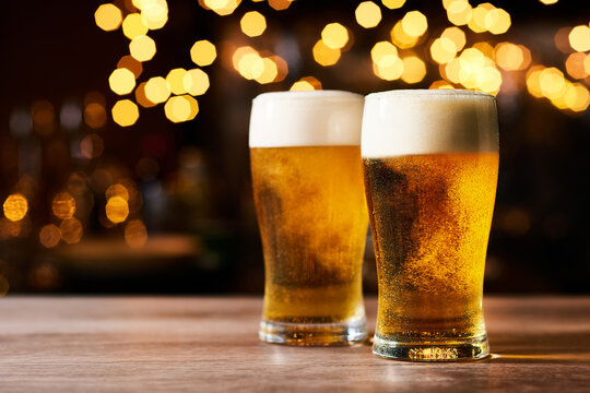 パブの店内で、木製のテーブルの上に二つのキラキラした美味しそうなビール。