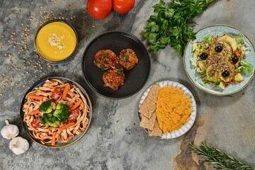 Colorful vegan meal with pasta, salad, and hummus.