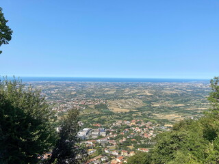 An amazing natural panorama of the San Marino suburbs surrounded by an endless blue sea strip on the horizon.