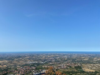 An amazing natural panorama of the San Marino suburbs surrounded by an endless blue sea strip on the horizon.