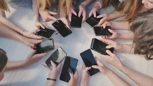 People holding their smartphones around a white table, using their devices and showing a sense of community.