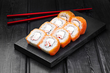 Japanese rolls, Philadelphia sushi made of salmon with crab meat and cheese on a black wooden background