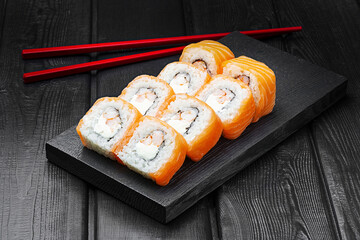 Japanese rolls, Philadelphia sushi with shrimp and cheese on a black wooden background.