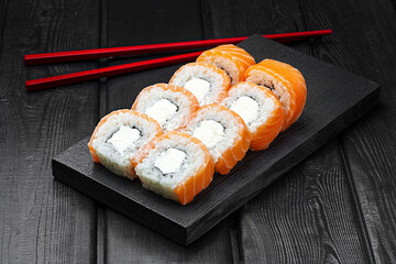 Japanese rolls, Philadelphia sushi with salmon and cheese on a black wooden background.