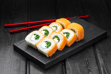 Japanese rolls, Philadelphia sushi with salmon, green onions and cheese on a black wooden background.