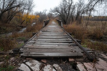 Fototapeta premium A dilapidated wooden bridge over a dried-up creek bed, symbolizing decay, history, and forgotten paths, with broken planks, overgrown weeds, and the remnants of a once vibrant landscape