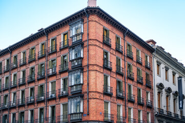 Old brick wall building featuring details of enclosed balconies, Madrid, Spain.
