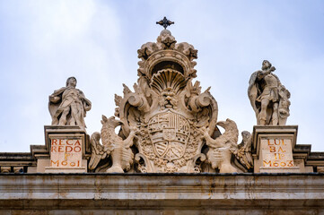 Ancient stone coat of arms and sculptures atop the Royal Palace, Madrid, Spain.