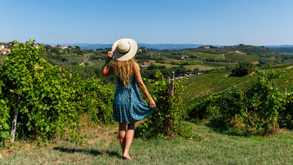 Woman with dress and hat in vineyard in Tuscany, Italy