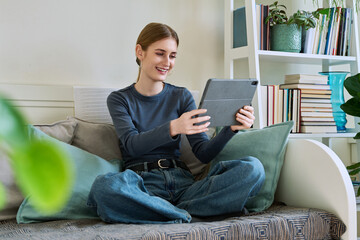 Teenage female student at home looking talking in web camera of digital tablet