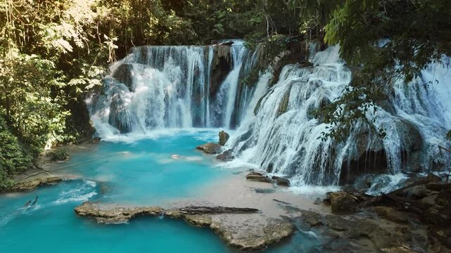 Amazing cascade waterfalls with clear blue water and wooden bridge in Central Sulawesi, drone view
