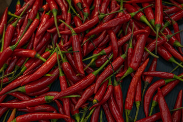 Top view of scattered red hot chili peppers, background.
