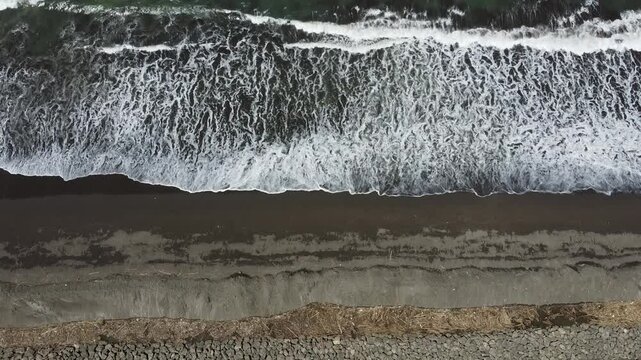 Aerial view of waves at Kemiren beach Cilacap, Indonesia with its black sand, 4k