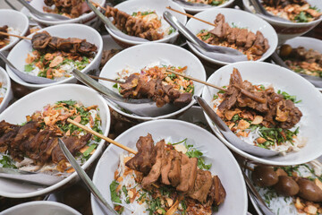 A vibrant display of soto with marinated meat skewers, garnished with fried shallots, green onions, and cilantro. This traditional Indonesian dish offers a rich, flavorful, and comforting meal.