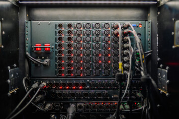 Close-up of a fully connected audio patch panel with numerous XLR ports and cables in a professional sound setup..