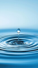 A delicate moment captured as a water droplet creates ripples in a tranquil blue pool