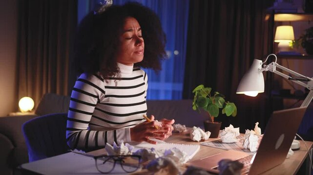 Sad young african american woman student or freelancer with lack of new ideas or creative block writing and crossed out at home Worried female with failed ideas working or studying at late night