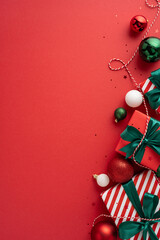 Stylish vertical Christmas presents with green ribbons and decorative ornaments on a vibrant red background creating a festive holiday atmosphere