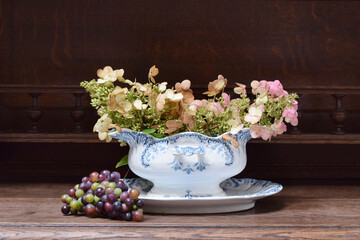 Autumn composition of flowers and grape  in vintage sauceboat