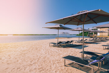 Beautiful luxury beach with sun loungers, sunbeds, umbrellas. White sand, sea view with horizon, blue sky, calm and relaxation. Inspiring beach resort hotel