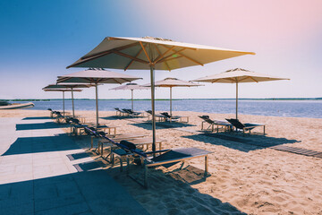 Beautiful luxury beach with sun loungers, sunbeds, umbrellas. White sand, sea view with horizon, blue sky, calm and relaxation. Inspiring beach resort hotel
