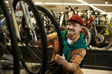 Young hipster man selecting new mountain bike in shop