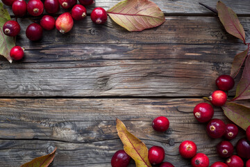 A wooden table with a red leaf and red berries on it